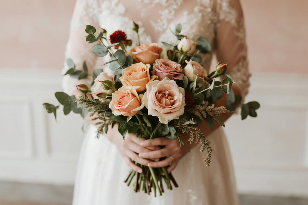 Bride holding elegant romantic wedding bouquet with blush pink roses and greenery