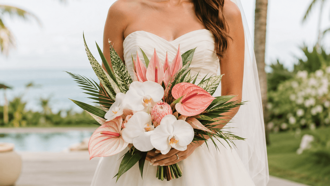 Bride holding an elegant tropical wedding bouquet with orchids, anthuriums, and lush greenery at a destination wedding venue.