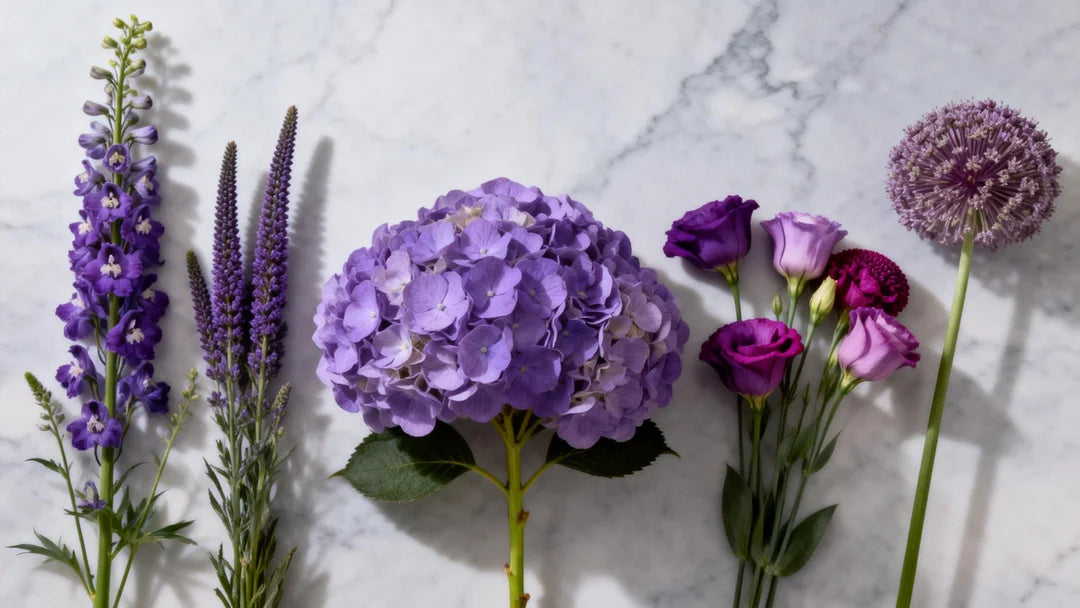 High-end editorial flat lay of purple wedding flowers arranged by shape on light grey marble—left tall delphinium and liatris; center fluffy hydrangea and lisianthus; right architectural allium and scabiosa.