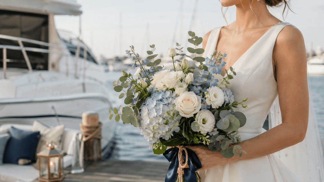 Nautical wedding flower arrangements with white roses, dusty blue hydrangeas, delphinium, and greenery at an elegant marina wedding.