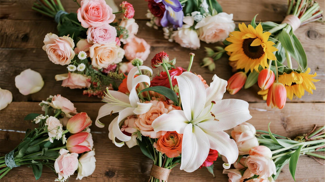 Vibrant flat lay of assorted wedding bouquets with roses, lilies, tulips, and sunflowers on wood